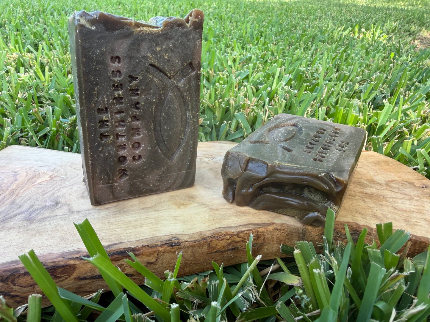 Two rustic handmade soap bars displayed on a wooden board 