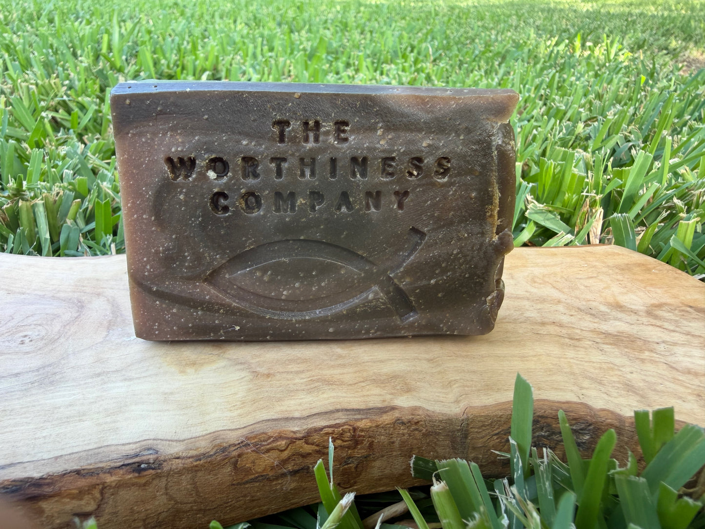 A half-bar of soap embossed resting on a cut wood slab.