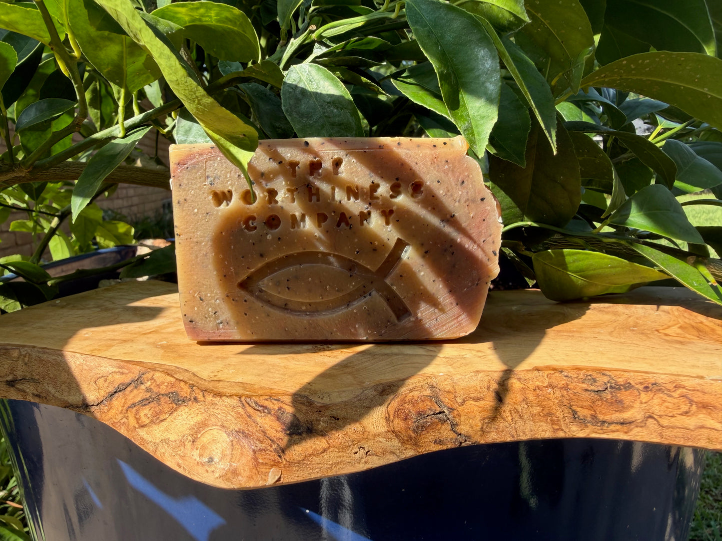 One rustic bar of handmade soap from The Worthiness Company, displayed on a wooden board.