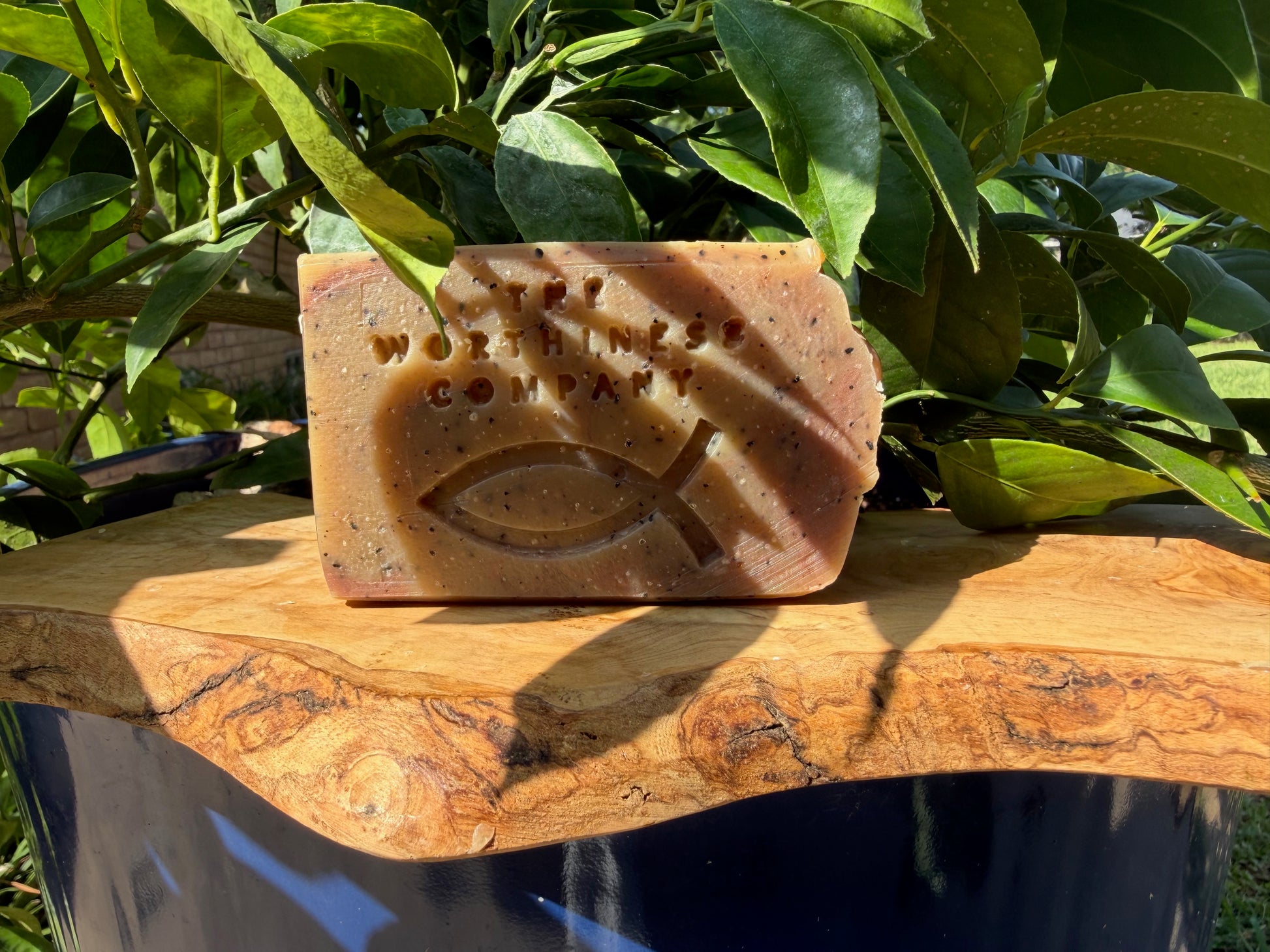 One rustic bar of handmade soap from The Worthiness Company, displayed on a wooden board.