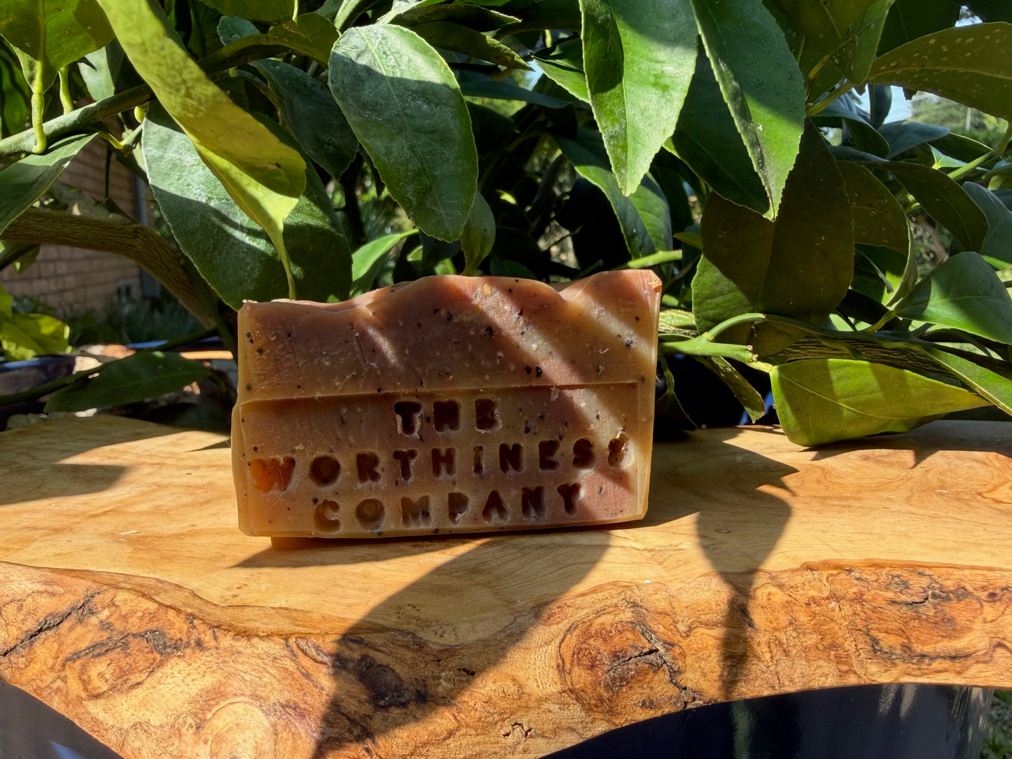 Half-bar of handmade soap from The Worthiness Company, displayed on a wooden board.