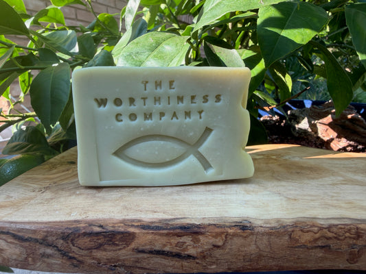 Light olive bar of soap sitting on a wooden slab.