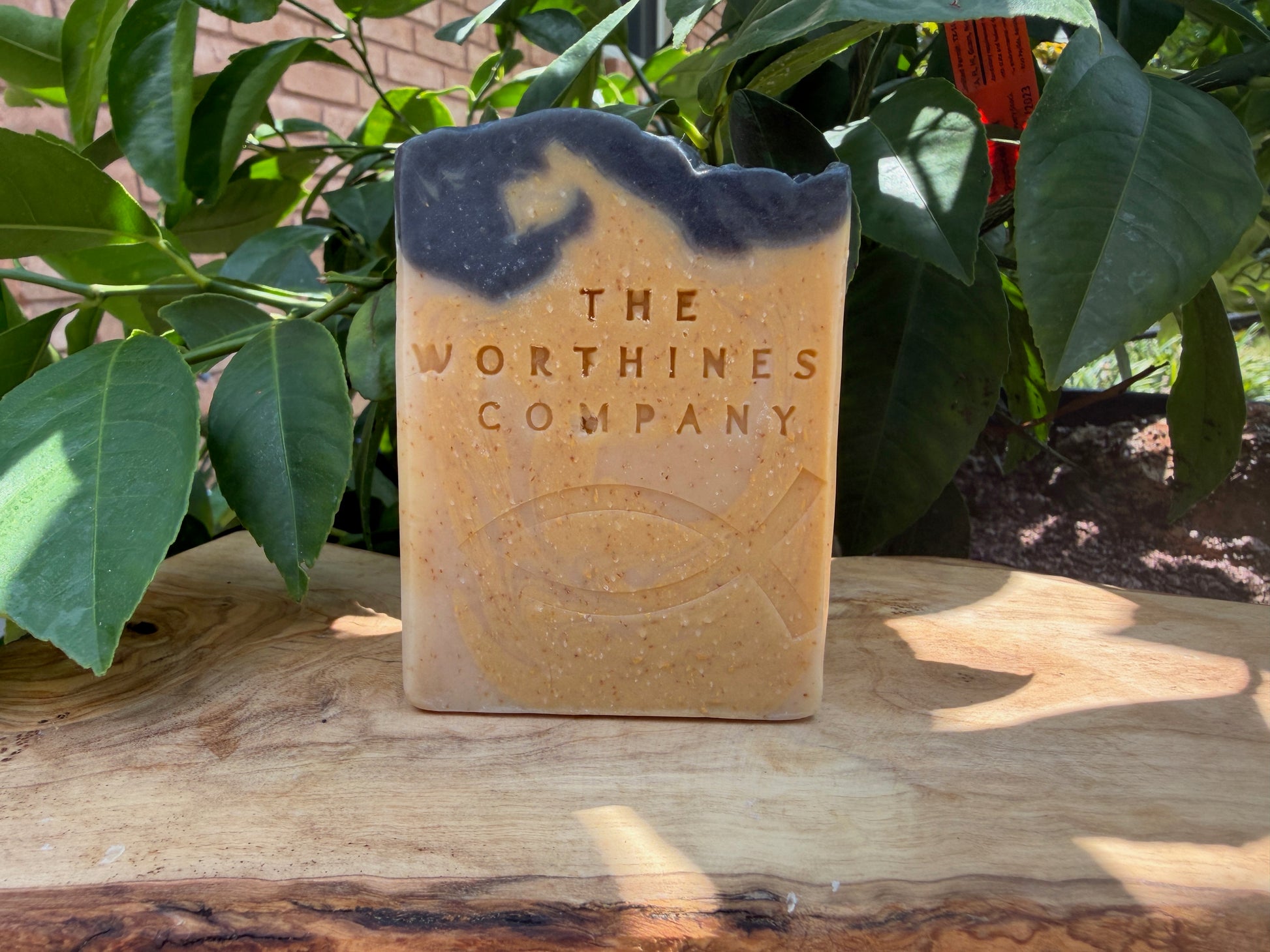 A rectangular handmade soap bar standing upright on a wooden surface. 